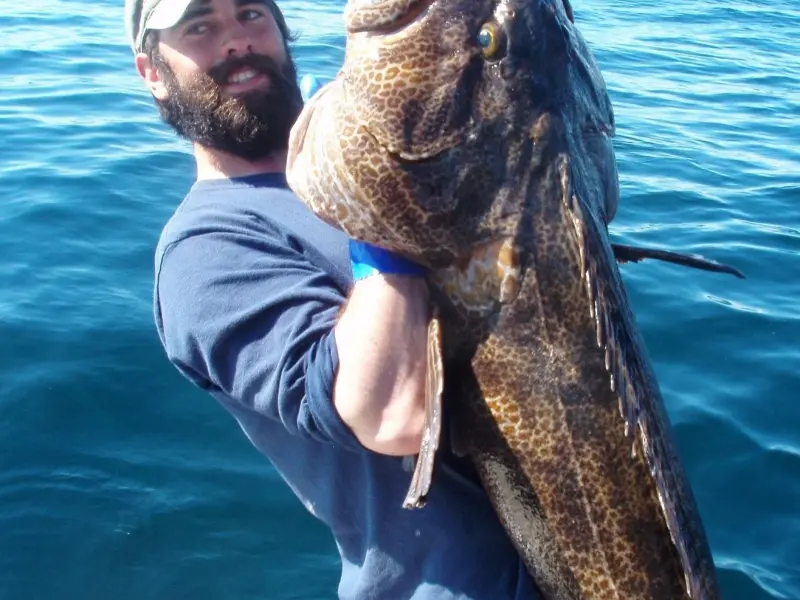 a man holding a fish on a boat in a body of water
