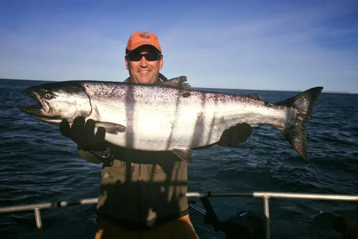 a man holding a fish on a boat in a body of water