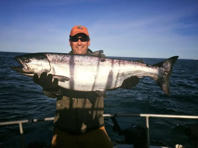 a man holding a fish on a boat in a body of water