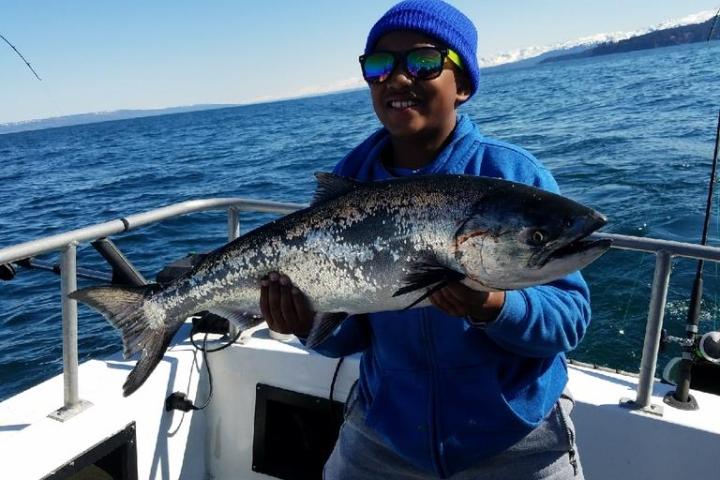 a person holding a fish on a boat in a body of water