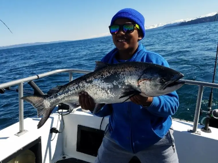 a person holding a fish on a boat in a body of water