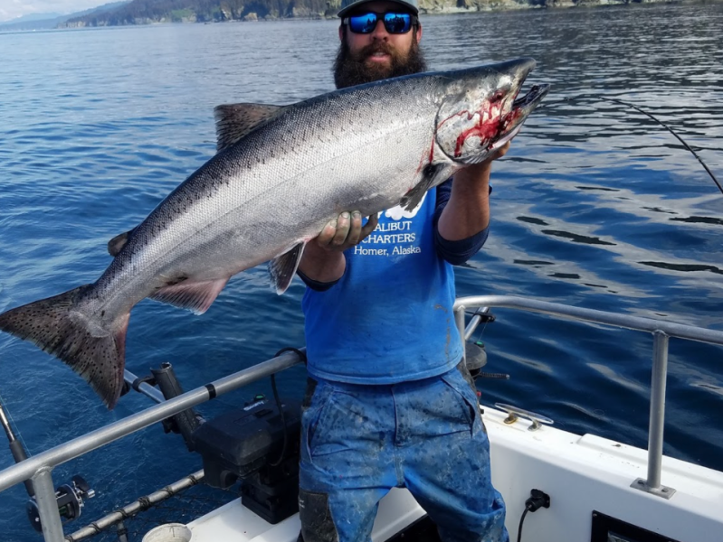 a man holding a fish on a boat in a body of water