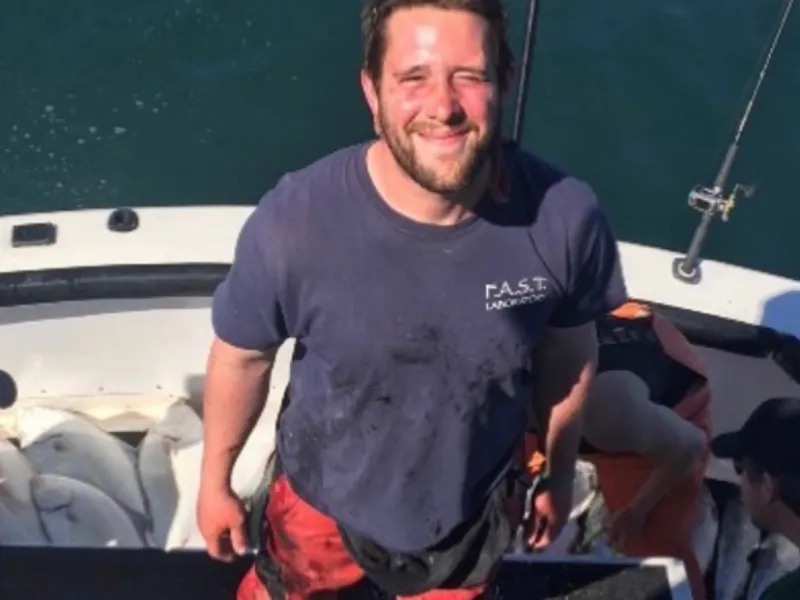 a man holding a fish on a boat